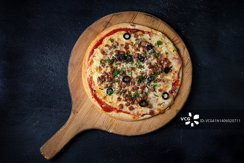 黑橄榄香肠披萨，木盘盛放，深色背景图片素材
