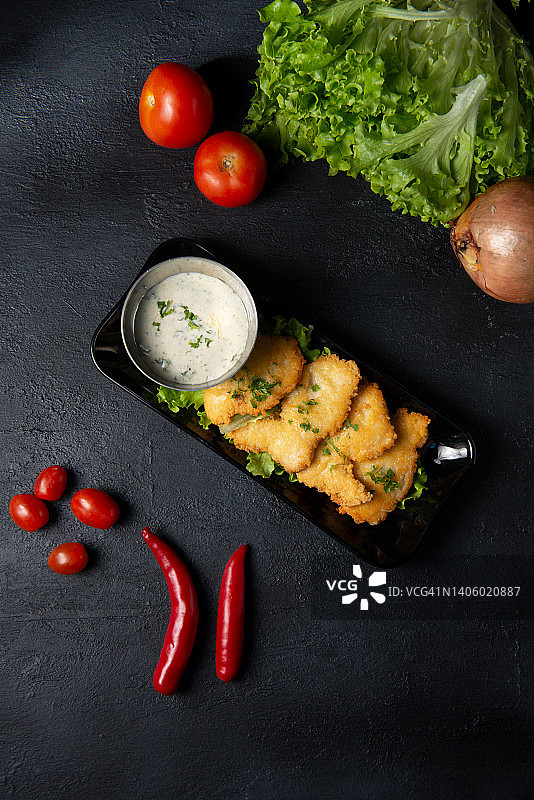 深色木桌上配酱汁的炸鱼图片素材