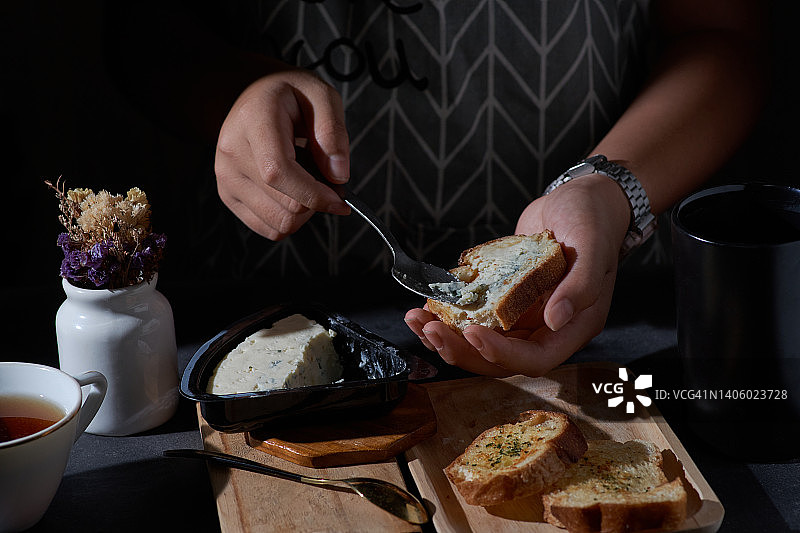 在大蒜面包上涂抹蓝纹奶酪图片素材