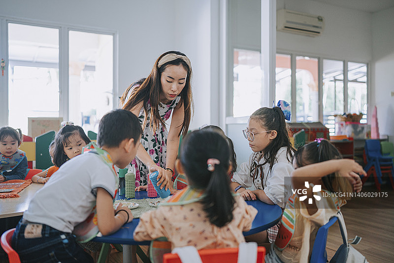 兴奋的亚洲蒙特梭利幼儿园学生等待老师在调色板上作画图片素材