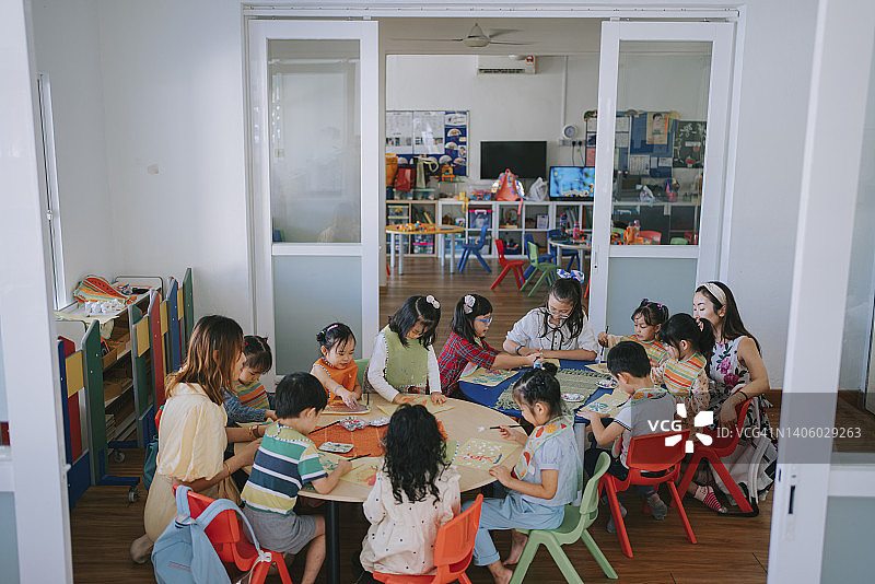 亚洲蒙台梭利幼儿园学生在教室里快乐绘画图片素材
