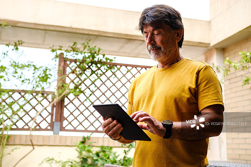 自信的男人在家中露台上用平板电脑查阅投资信息图片素材