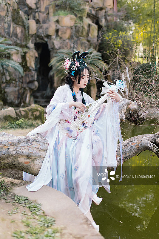 身穿汉服的美女在公园里弹奏琵琶图片素材