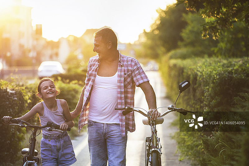 父女在自行车道上推着自行车玩耍图片素材
