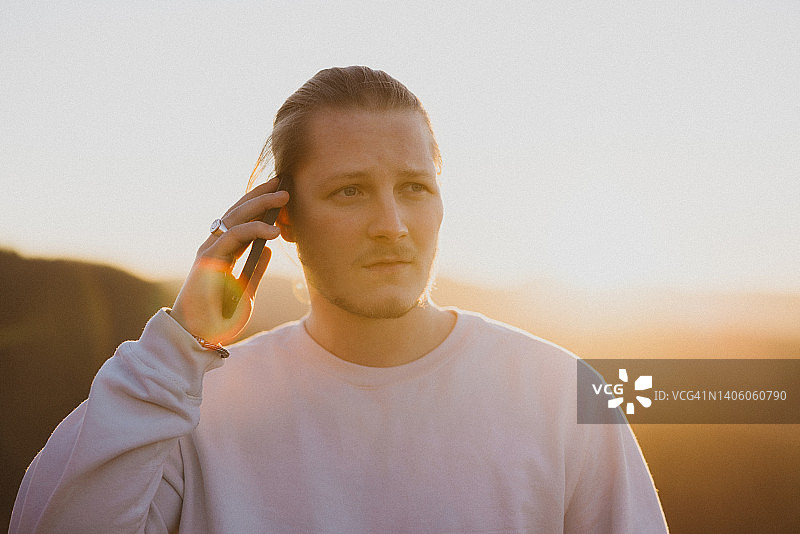 表情严肃的年轻男子在日落时进行商务通话图片素材