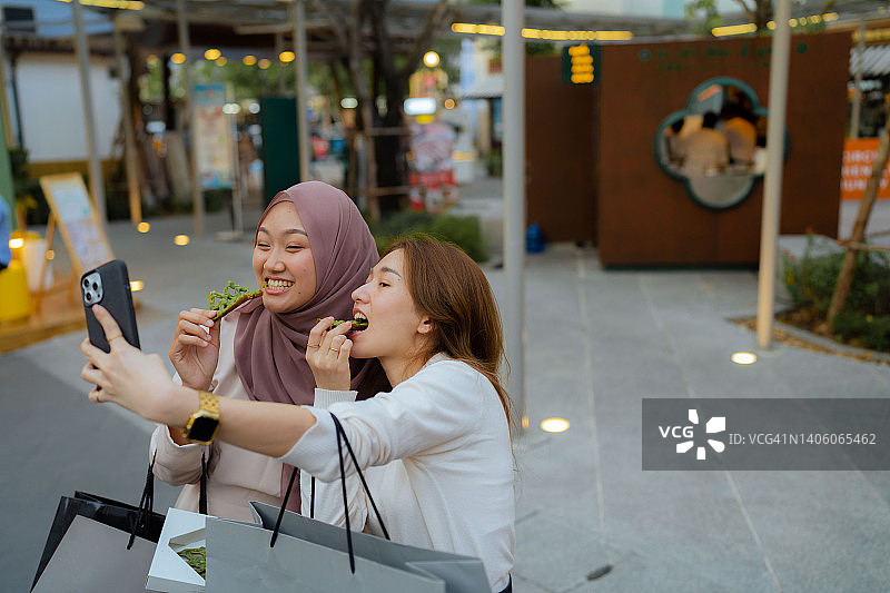 年轻女性在城市购物并一起吃华夫饼图片素材
