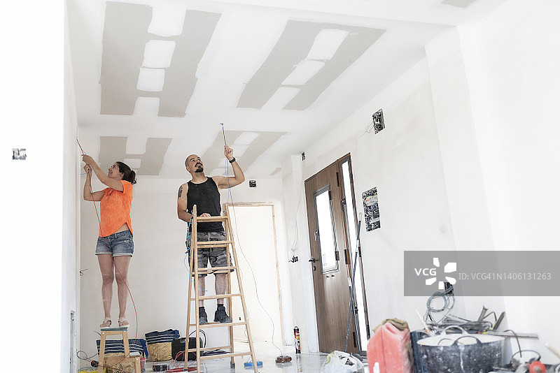 新婚夫妇在指导下安装电缆，改造新家图片素材