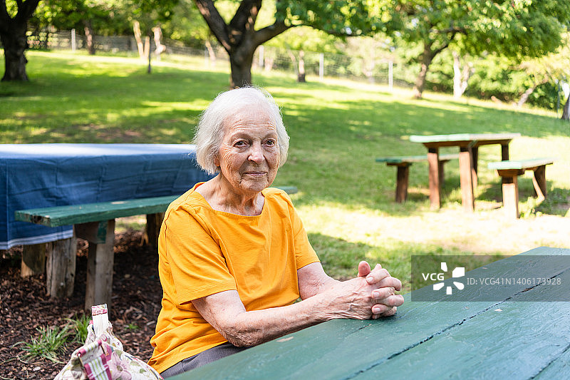 坐在花园餐桌前的中老年女性肖像图片素材