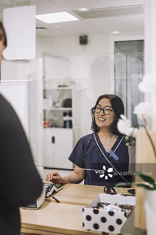 微笑的女接待员戴着眼镜在医院结账处协助病人图片素材
