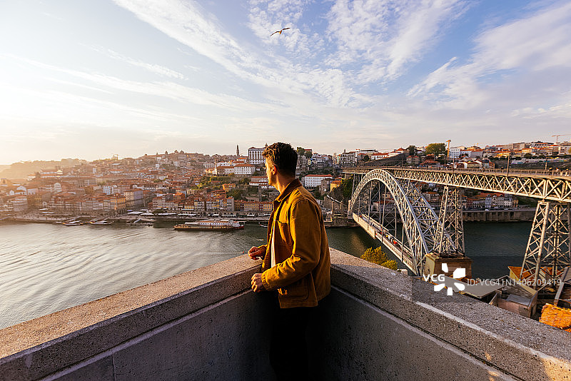 男子在葡萄牙波尔图镇欣赏杜罗河和路易一世大桥的日落图片素材