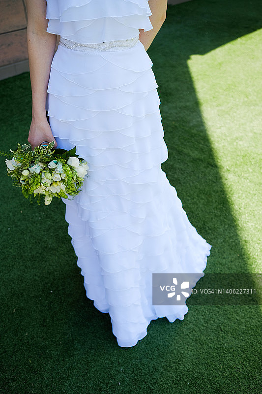 女孩或女人手中的白色鲜花花束。新娘身穿华丽礼服，在户外手捧玫瑰和绿叶的结婚花束图片素材