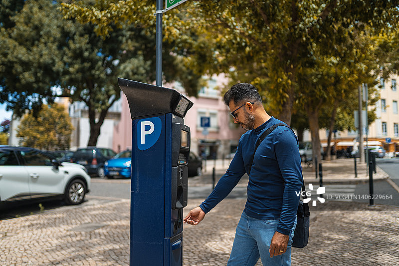 在葡萄牙里斯本，男子在专用付费机上用硬币支付停车费图片素材