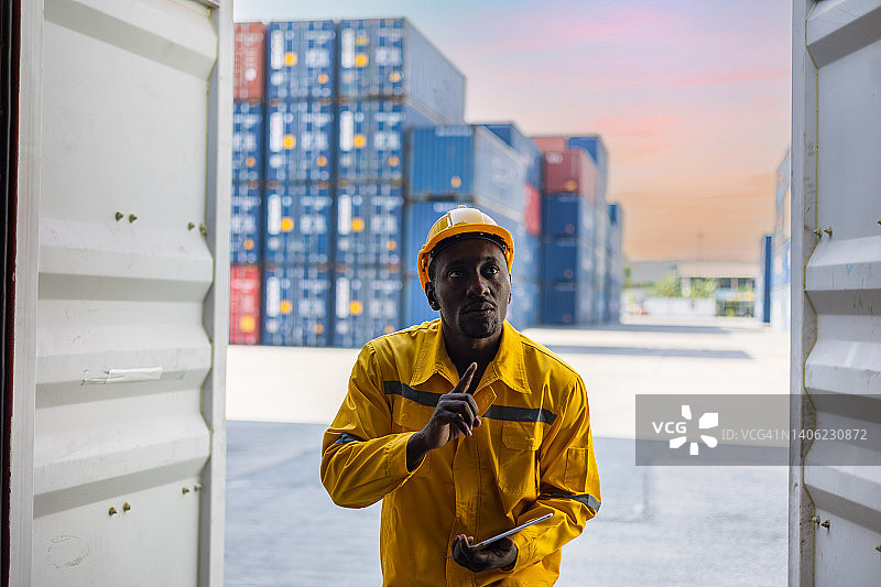 货运站的运输工人正在检查时间表集装箱运输货物。图片素材