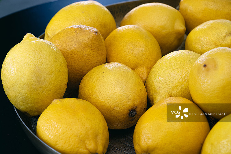 厨房餐桌上的成熟黄色柠檬特写：丰收节的水果，金属盘上的完整生态水果，产地直达餐桌，自然背景之美图片素材