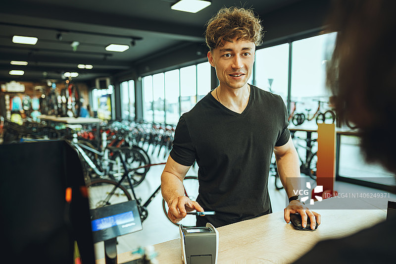 年轻男人在自行车店付款图片素材