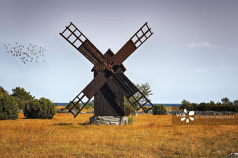 棕色木制风车，傍晚天空中的鸟群，布格斯维克，哥特兰岛，瑞典图片素材