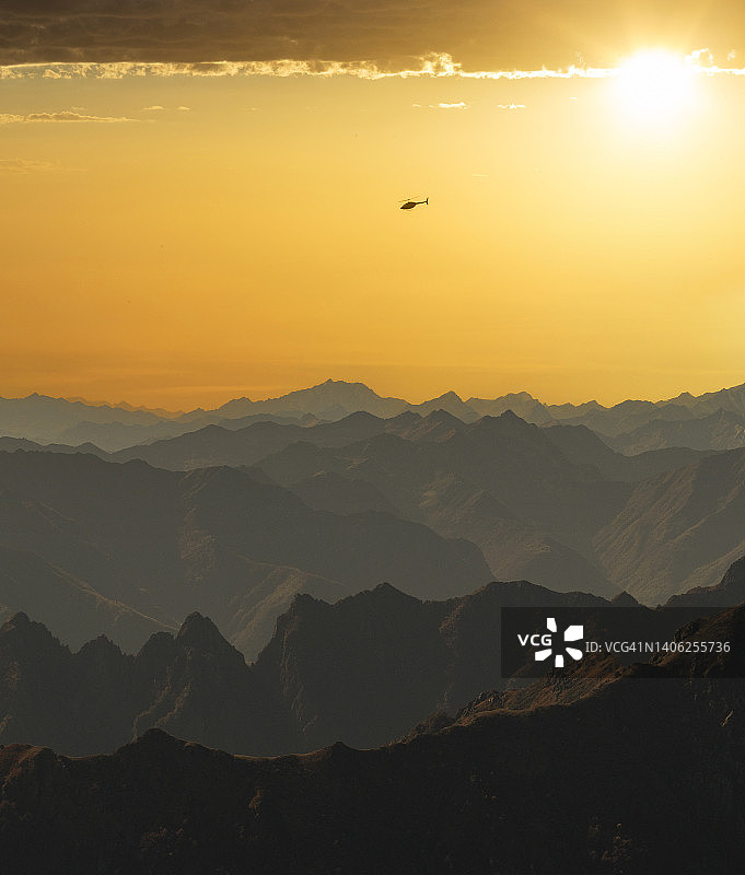 日落时分山脉上空的直升机图片素材