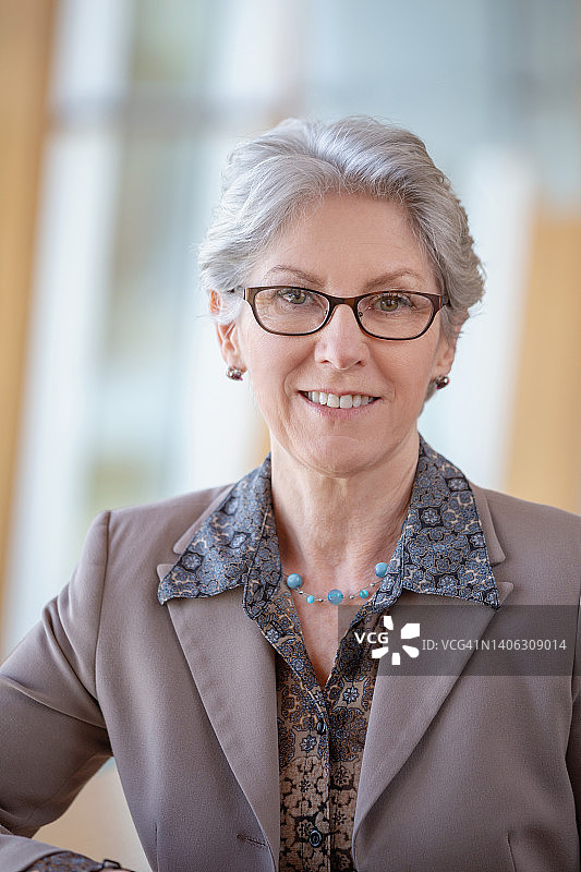 戴着眼镜站在办公室大厅的年长的白人女商人肖像图片素材