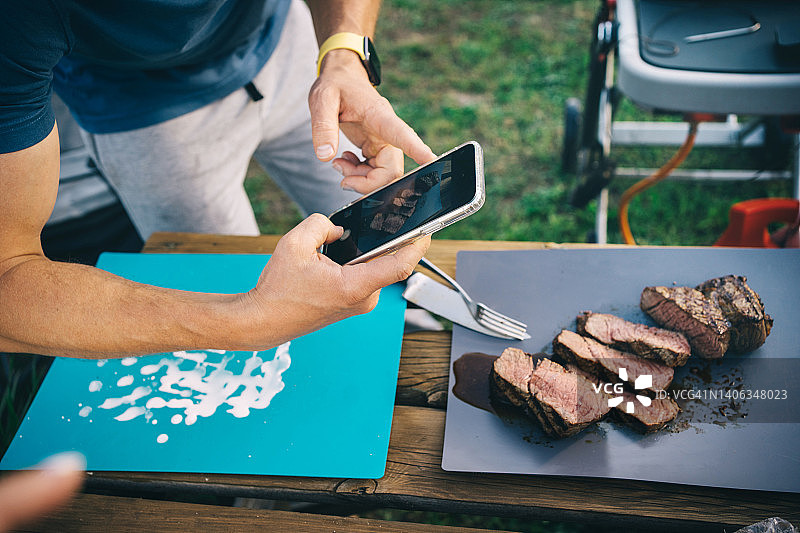 父亲用智能手机拍摄做好的牛排，父亲节的节日餐图片素材