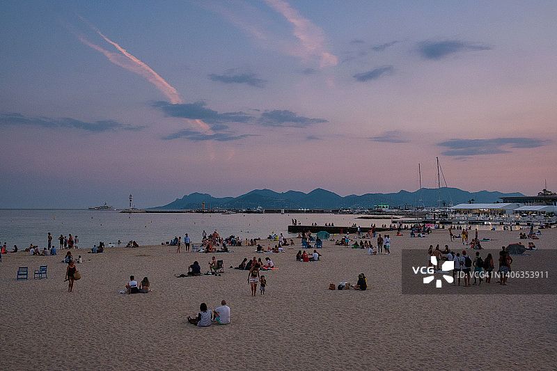 人们在海滩观看日落，远处有山图片素材