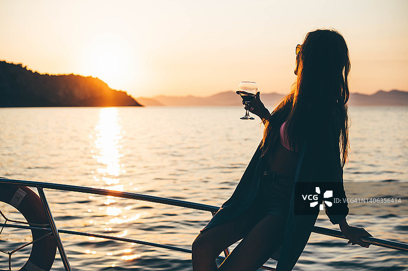 女人在帆船上欣赏日落时喝葡萄酒图片素材