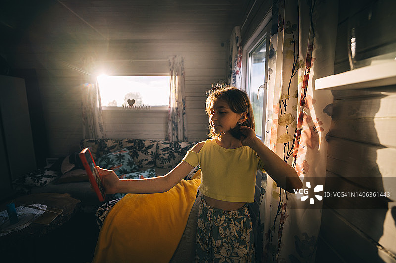 阳光洒进房间，女孩用手机视频通话图片素材