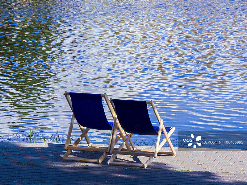 两把躺椅，站在走道上，背景是蓝色的河流图片素材