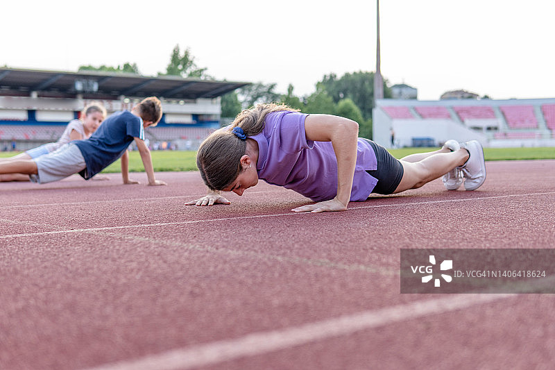 年轻跑步者在赛道上做俯卧撑图片素材