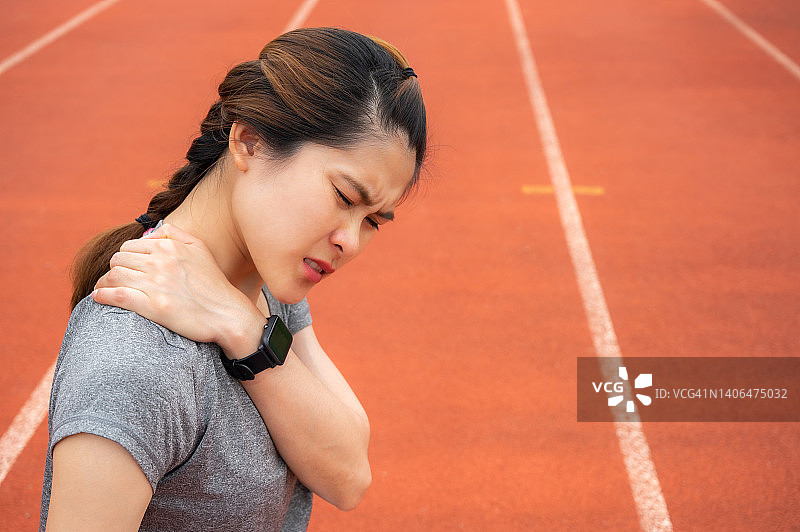 在体育场艰苦训练后，肩颈疼痛的亚洲女跑步者图片素材