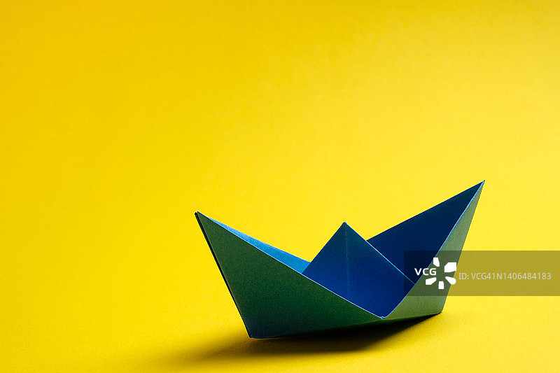黄色背景上手工制作的明亮彩色纸船，商业竞争与团队领导概念，可复制空间图片素材