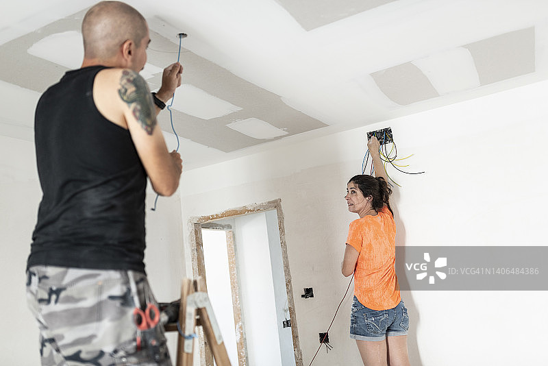 新婚夫妇在指导下安装电缆，改造新家图片素材