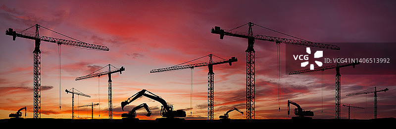 日落时分起重机和挖掘机的建筑工地全景图片素材