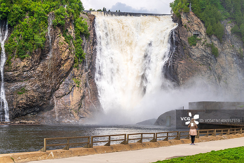 戴着帽子，背景是瀑布的女人图片素材