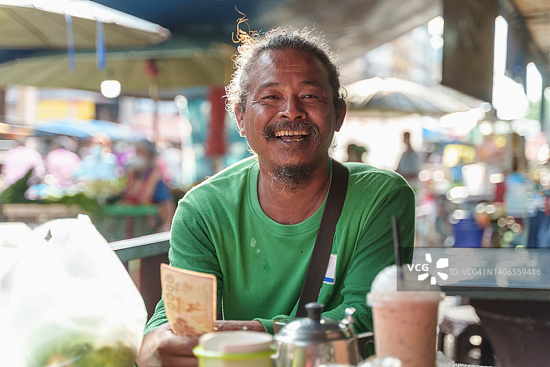 从当地商业银行贷款后，拿着一叠钱感到高兴的年长的亚洲男工人图片素材