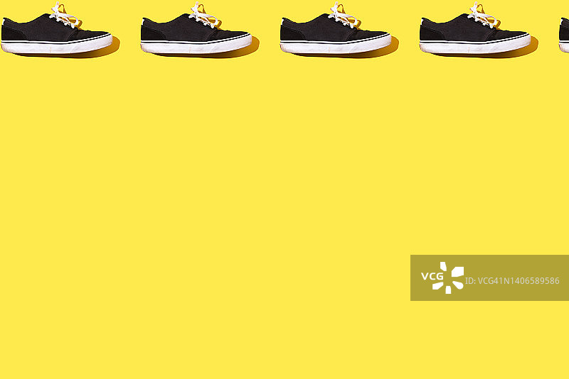 黄色背景上的黑白帆布橡胶滑板运动鞋图案图片素材