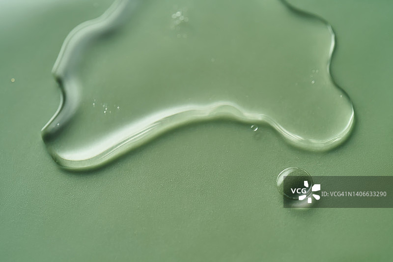 绿色背景上的一滴化妆品液体凝胶或卸妆水图片素材