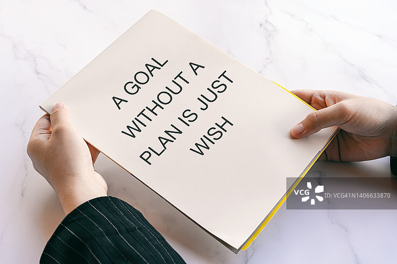 手持写有生活语录的笔记本——没有计划的目标只是一个愿望图片素材