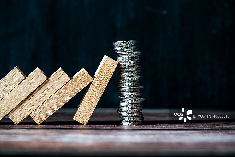 硬币堆叠平衡阻挡多米诺骨牌倒塌：金融稳定概念图片素材