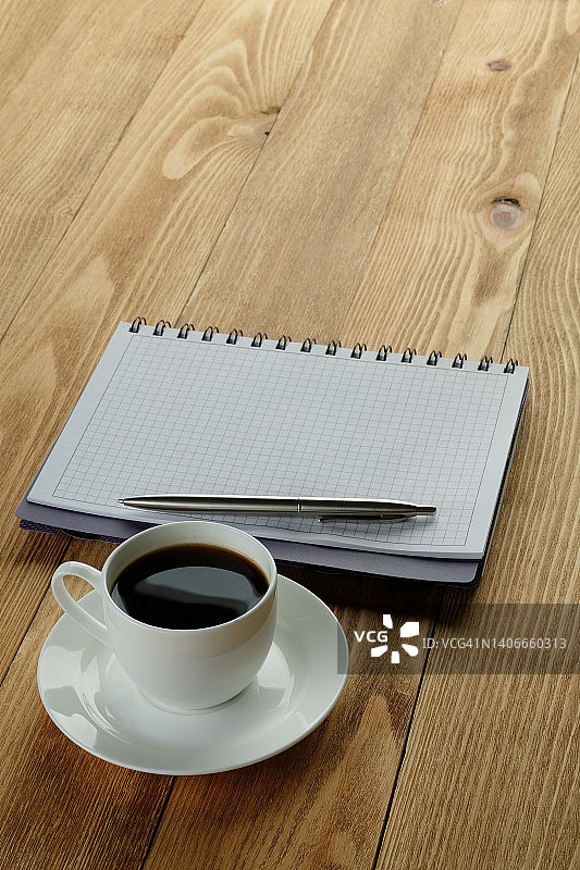 木制餐桌上的笔记本、笔和黑咖啡：商务人士或经理的办公用品，咖啡休息或商务会议，制定一日计划图片素材