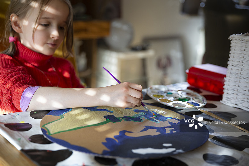 儿童在餐桌上将地球绘画到圆形纸板上图片素材