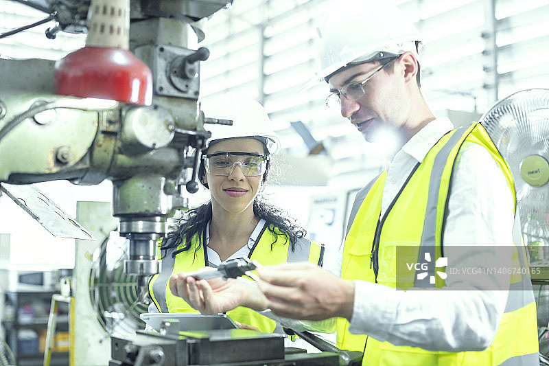 男女工程师用游标卡尺测量精密汽车零件图片素材