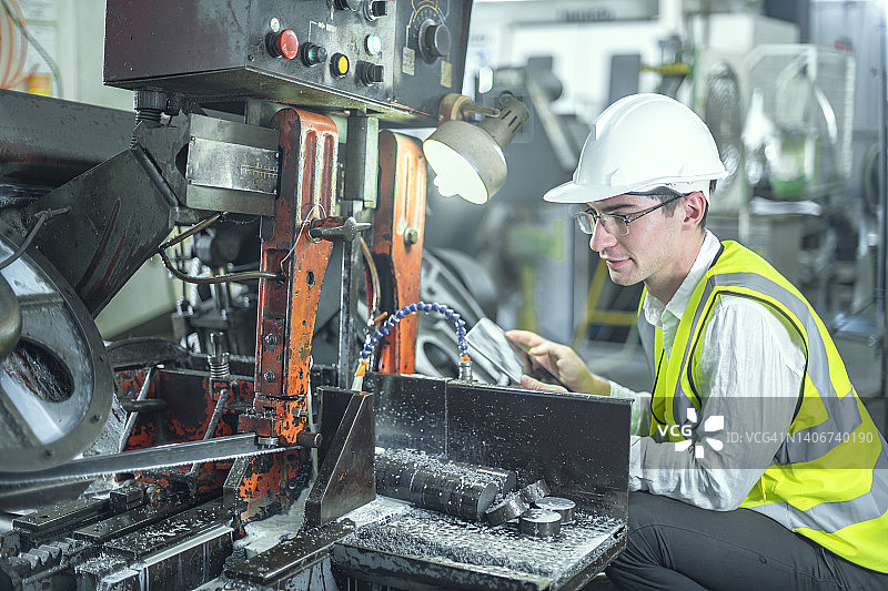 戴白色安全帽的男工程师检查并控制机器按预期工作图片素材