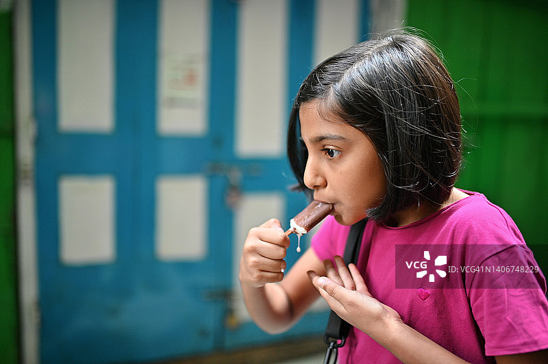 女孩边走路边吃冰淇淋图片素材