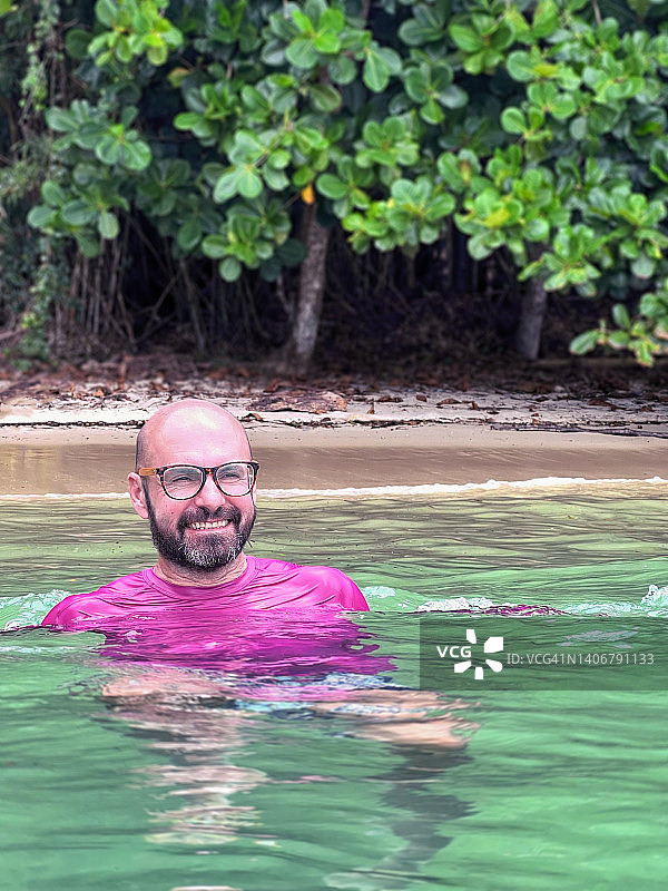 男人在靠近有树木的海滩游泳图片素材