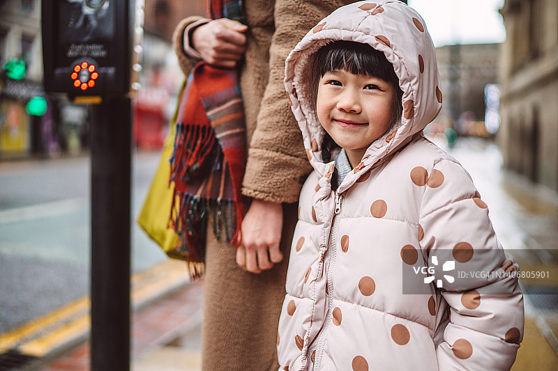 可爱的女人在市中心街道与妈妈一起等红绿灯时高兴地对着镜头微笑图片素材