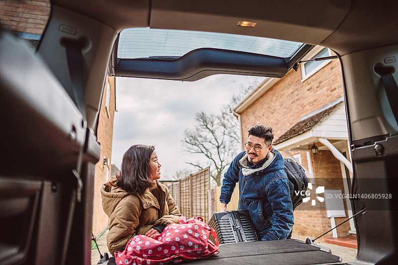 可爱的女孩帮助她的爸爸将包和手提箱装到汽车后备箱中，准备公路旅行图片素材