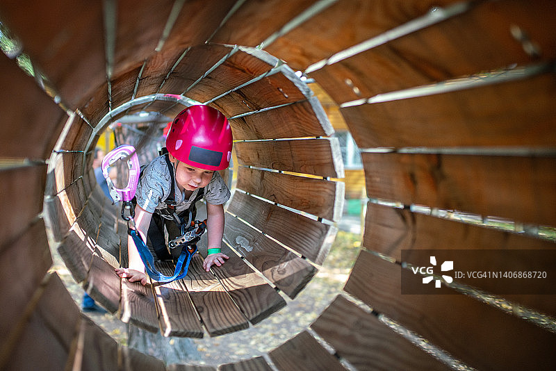可爱的小男孩在冒险公园的日落时分通过障碍训练图片素材