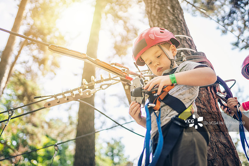 可爱的小男孩在冒险公园的日落时分通过障碍训练图片素材