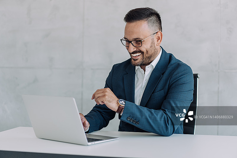 在现代办公室使用笔记本电脑的成功商人图片素材