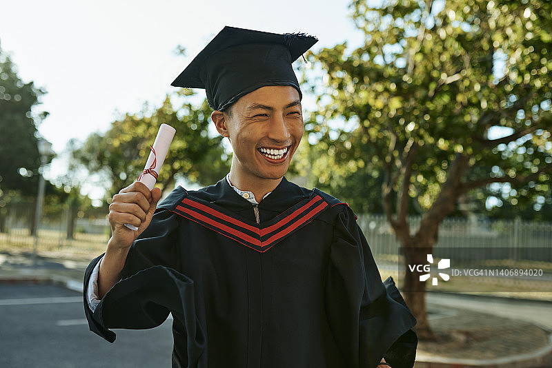 毕业典礼上，身穿礼服、头戴帽子的年轻毕业生庆祝成功图片素材